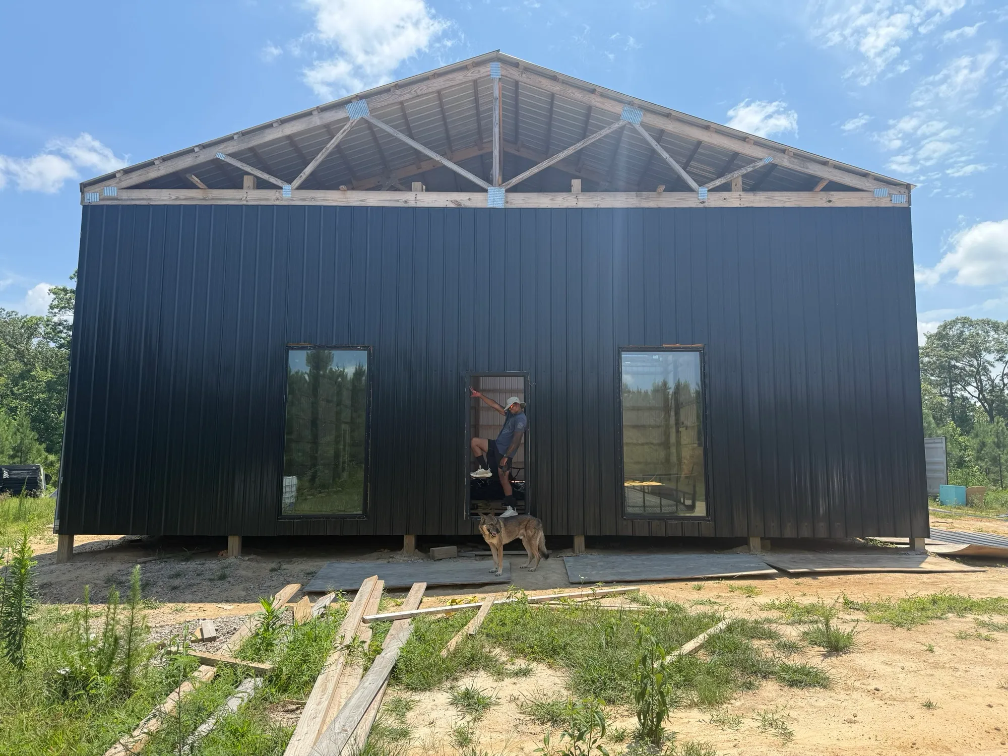 A new black metal building going up at the Grove, with a dog keeping watch out front