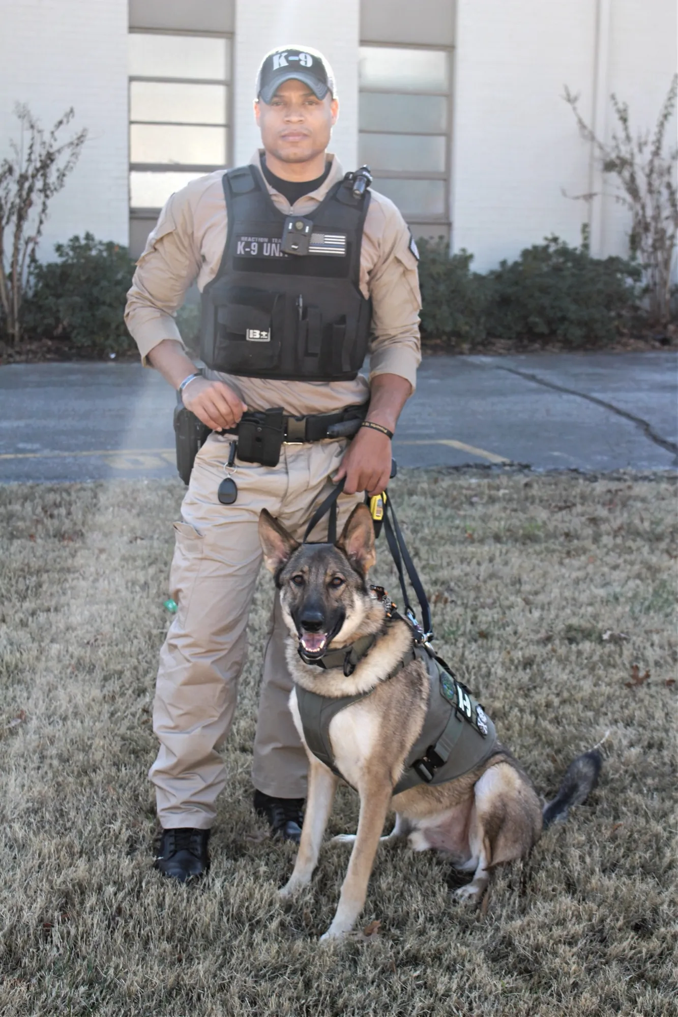 Josh in K-9 gear standing beside a German shepherd in a harness